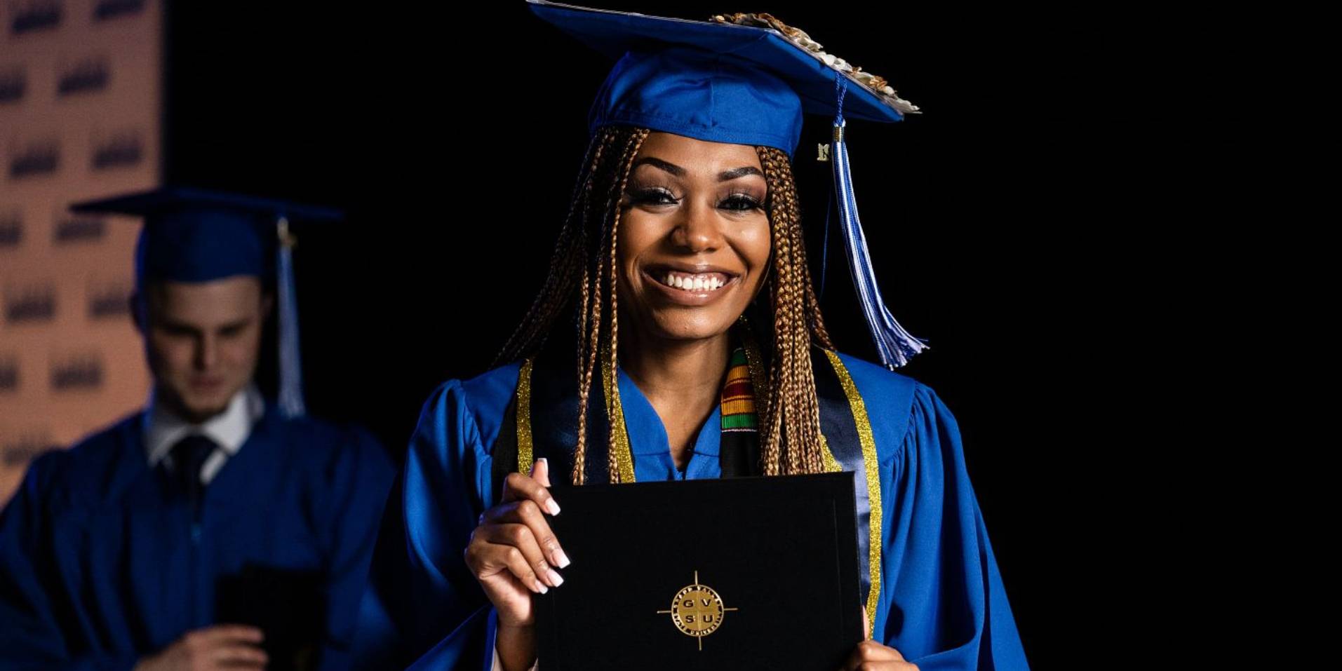 Woman smiling during graduation with diploma in hand